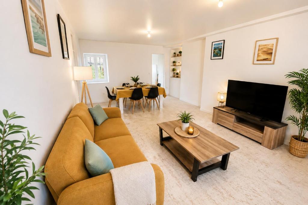 a living room with a couch and a tv and a table at La Maison du Clain in Jaunay-Clan