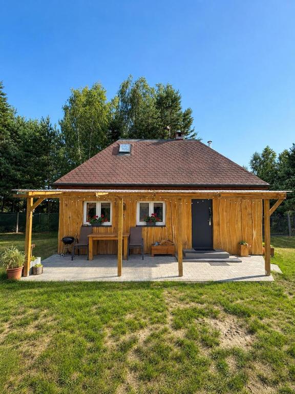 a large wooden house with a patio in a field at Domek letniskowy Sarnowo, Skępe in Skępe