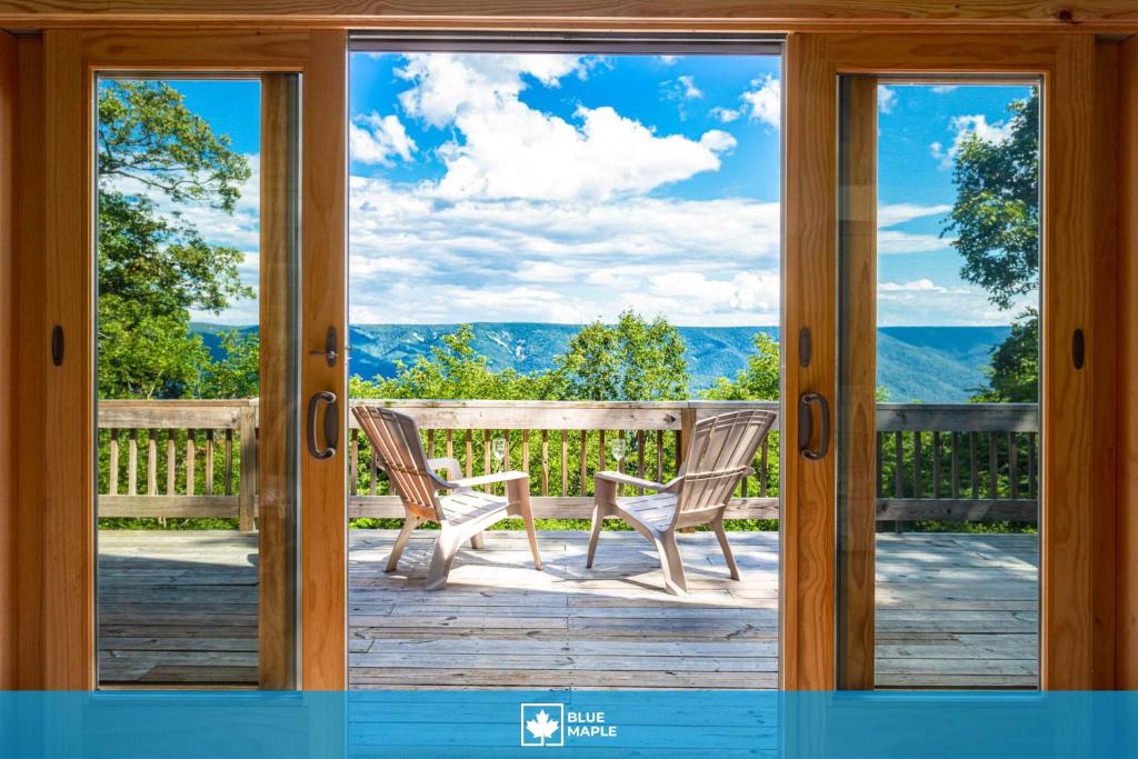 a sliding glass door with two chairs on a porch at 3BR cabin w scenic deck and pet-friendly in Great Cacapon
