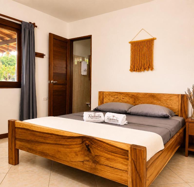 a bedroom with a wooden bed with two pillows on it at Hotel Campestre Alameda in Támesis