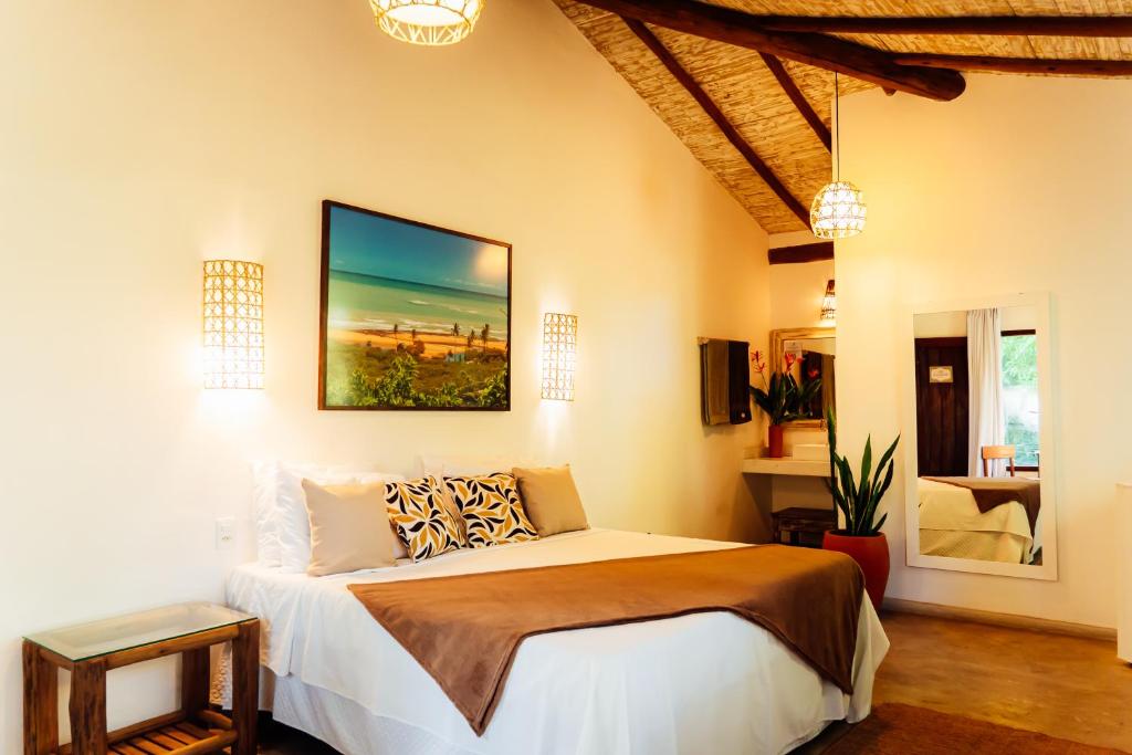 a bedroom with a bed and a painting on the wall at Pariri Suites in Trancoso