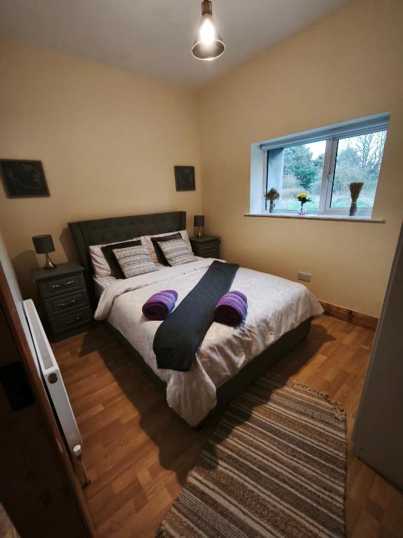 a bedroom with a bed with purple pillows and a window at mitchelstown castle chalet in Mitchelstown