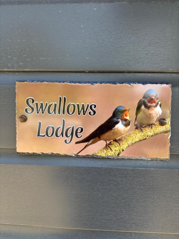 two birds sitting on a sign with the words swallows lodge at Swallows Lodge in Bathgate