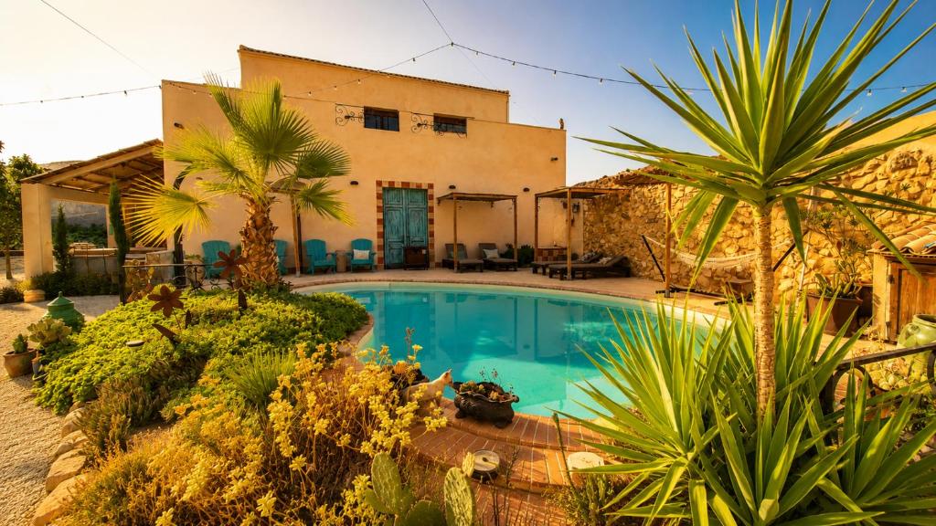 a villa with a swimming pool and palm trees at Casa Rodriguillo Pinoso - Boutique B&B in Pinoso