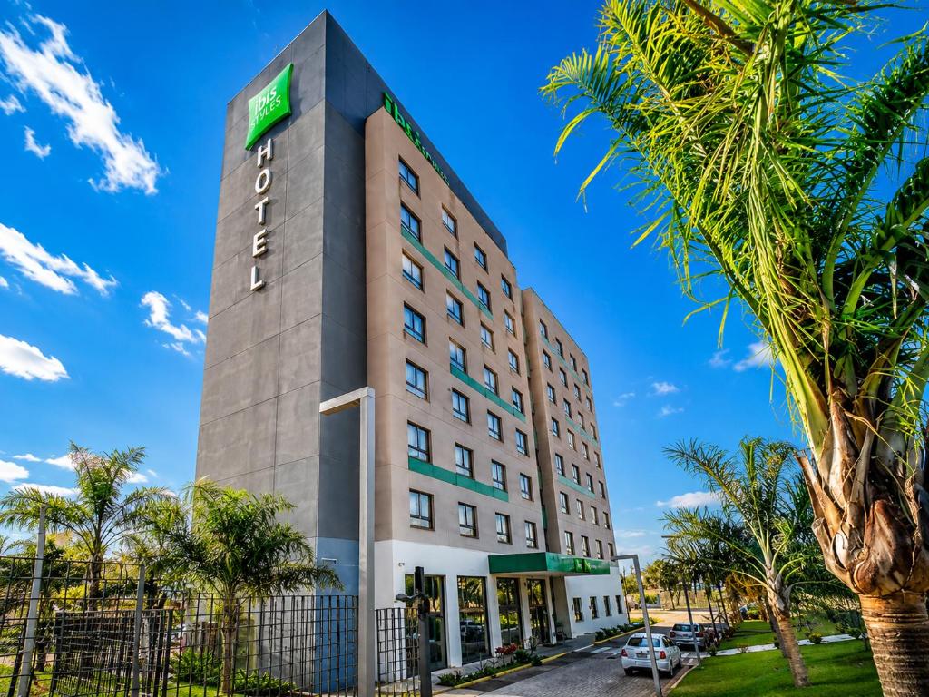 a hotel with a palm tree in front of it at ibis Styles Rondonopolis in Rondonópolis