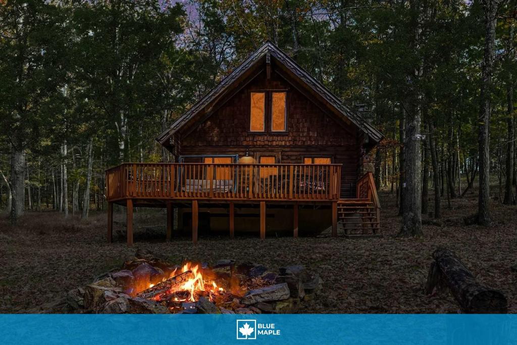 a fire burns in front of a log cabin at Log Cabin w Loft, Hot Tub, Deck, Fire Pit, & WiFi in Great Cacapon