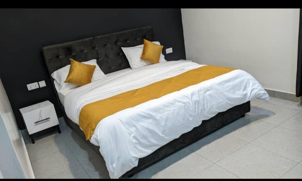 a large bed with yellow and white sheets and pillows at Mansarda parkview Hotel in Nyagatare