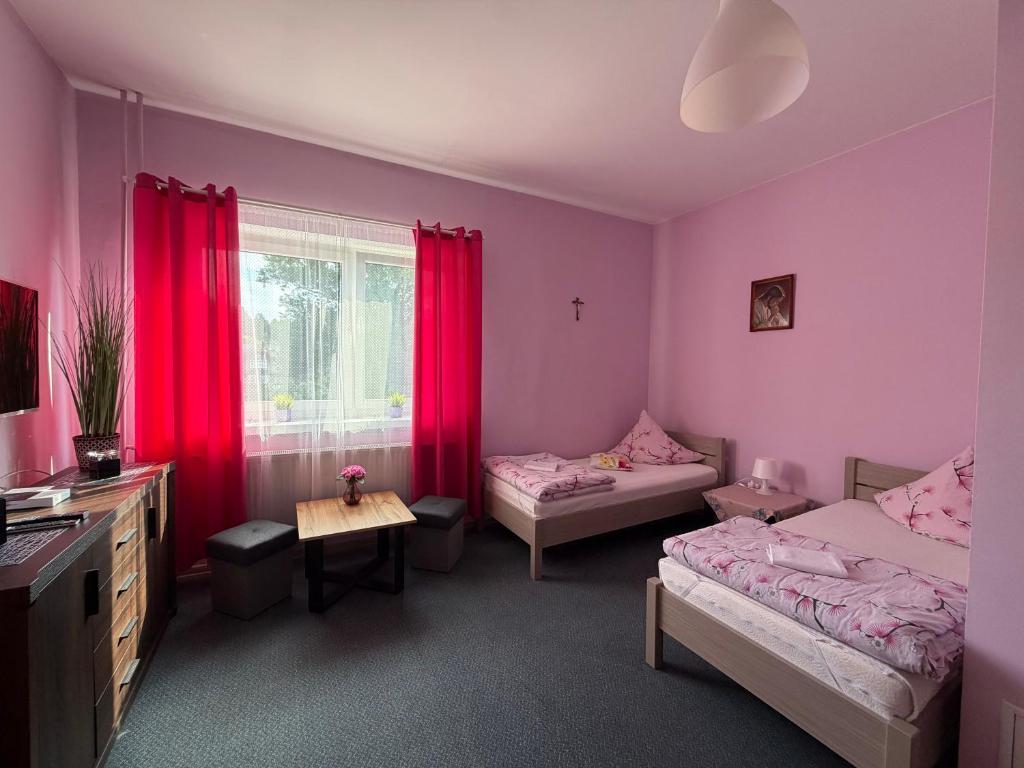 a bedroom with two beds and red curtains at Agroturystyka ''Dom Pod Karpiem'' in Zagórze Śląskie