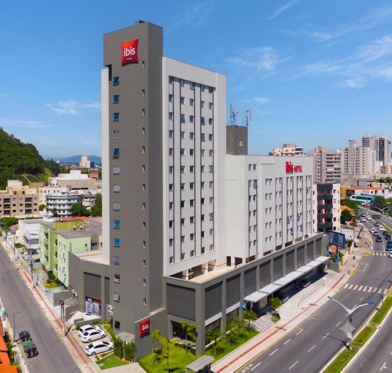 a large white building with a red sign on it at ibis Navegantes Itajai in Itajaí