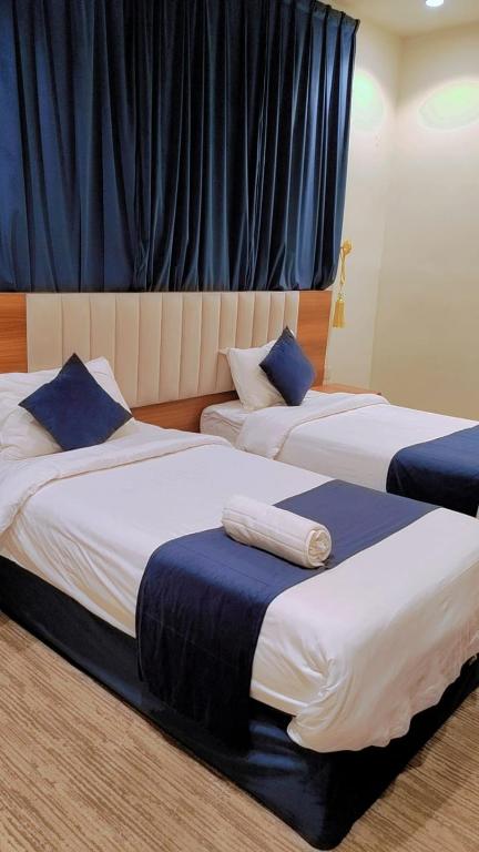 zwei Betten mit blauen Kissen in einem Zimmer in der Unterkunft لافيرا للشقق الفندقيه - Lavera Apartments in Al-'Ula