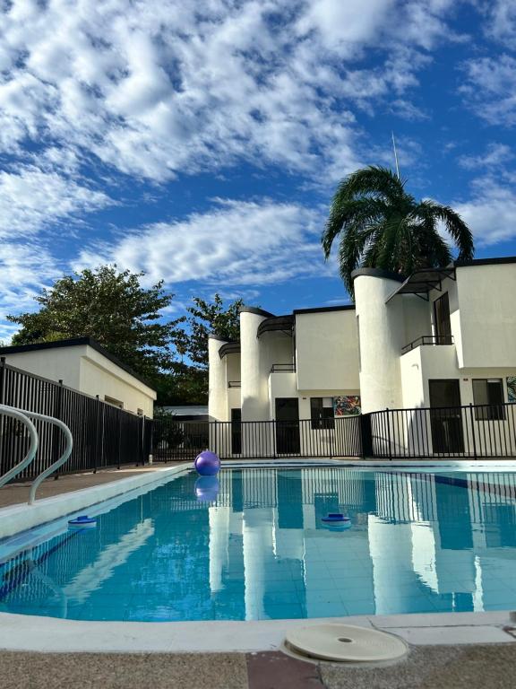 a swimming pool with a palm tree and a building at Villas del Oasis in Ricaurte
