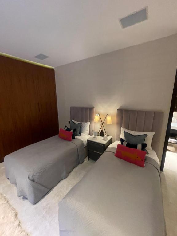 a bedroom with two beds and a table with a lamp at Saint Peter Hotel in London