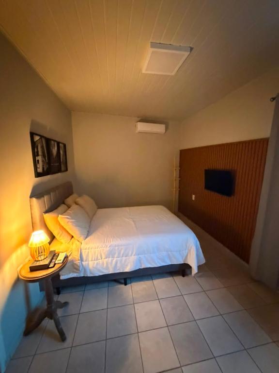 a bedroom with a bed and a table with a lamp at Apto centro 03 in Tubarão