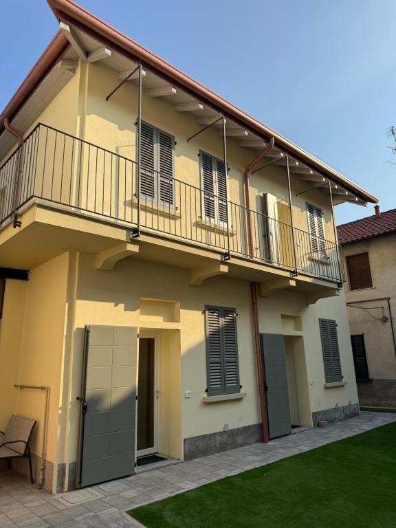 a yellow house with a balcony and a lawn at Les Maisons Manzoni in Magenta