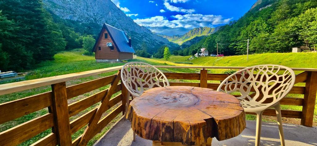 a wooden table with a tree stump sitting on a fence at Djedina Gora Cabins in Poda