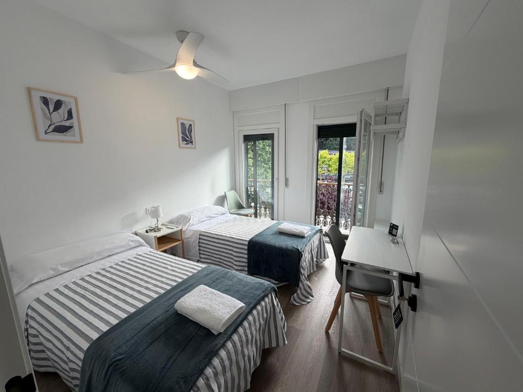 a bedroom with two beds and a desk and a window at Rubín 21 in Redondela