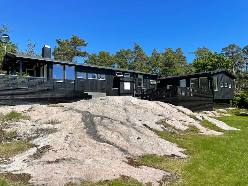 a black house on top of a rock at Peaceful seaside cabin with guest house - large private outdoor areas and boat available on request in Eigebrekk