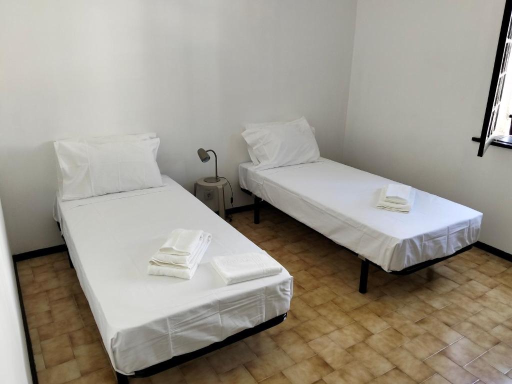two beds in a room with white sheets at Conceição Guesthouse in Tavira