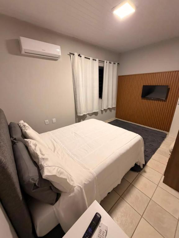 a bedroom with a white bed and a couch at Apart 102 CENTRO in Tubarão