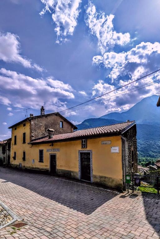 a building on a street with mountains in the background at Antica osteria in Primaluna