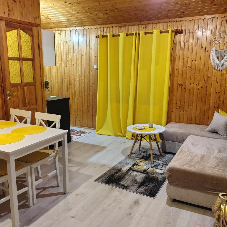 a living room with a table and a yellow curtain at Domek u Prezesa in Kłótno