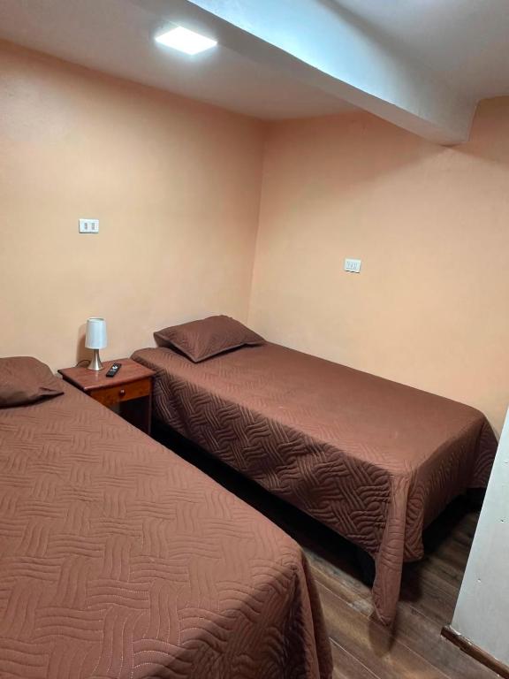 a hotel room with two beds and a lamp on a table at NurHome in Mejillones