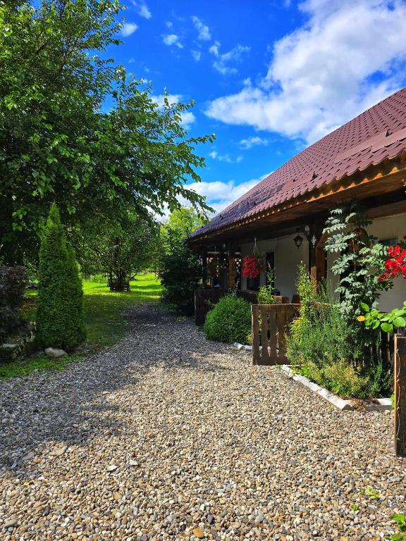 a house with a gravel driveway next to a building at La Romaneasa in Săpânța