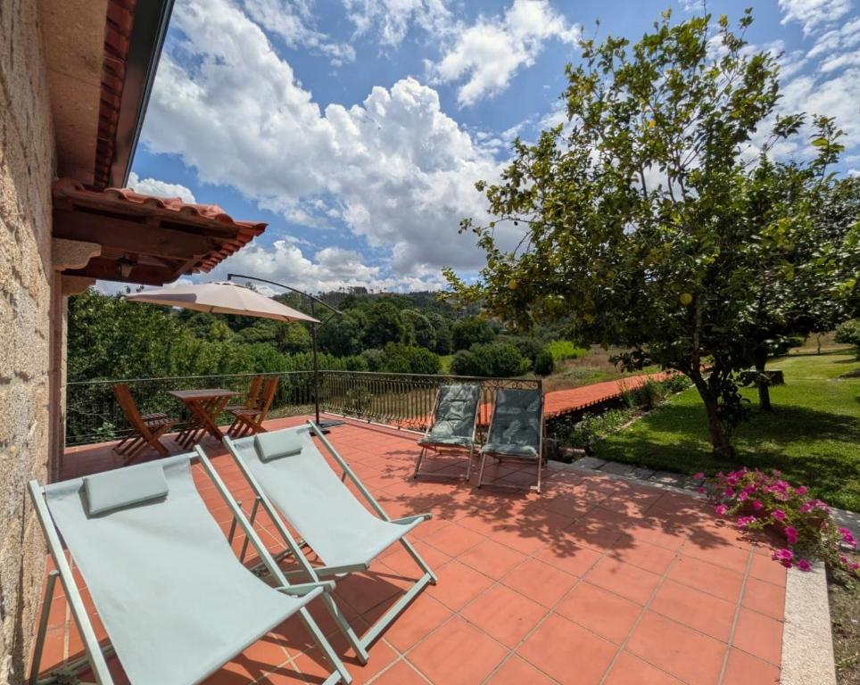 a patio with two lounge chairs and an umbrella at Casa da Sofia in Ponte da Barca