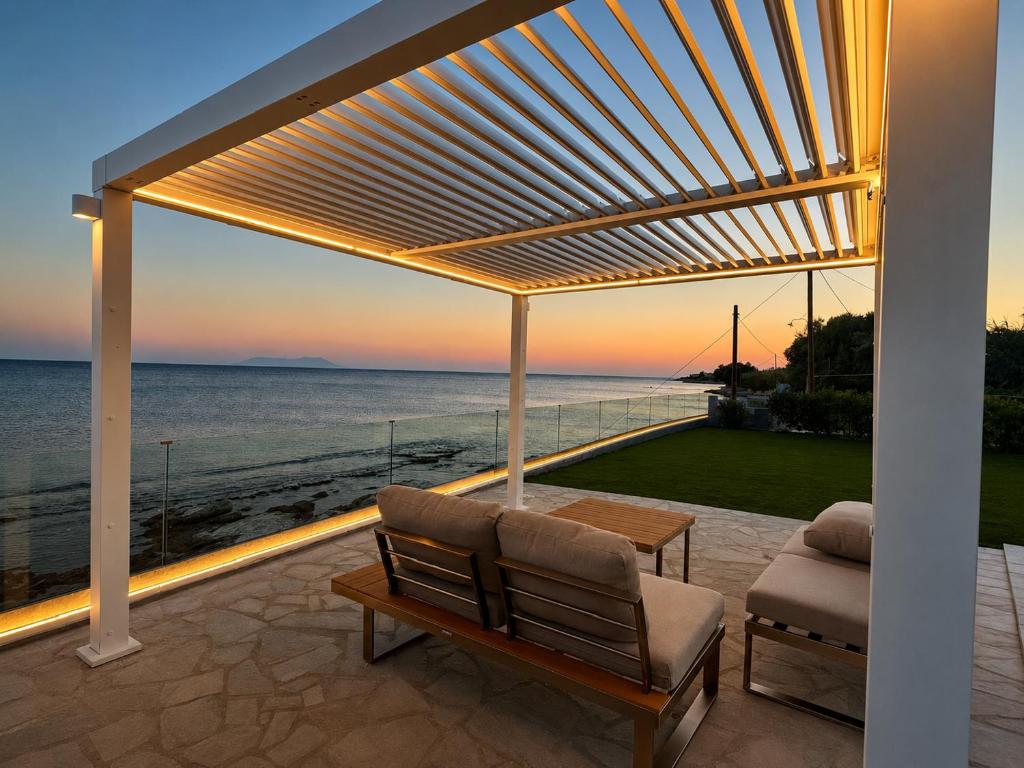 a pergola on a patio with a view of the ocean at Aegean Horizon Seafront Luxury Villa Plomari Garden Level in Trýgonas