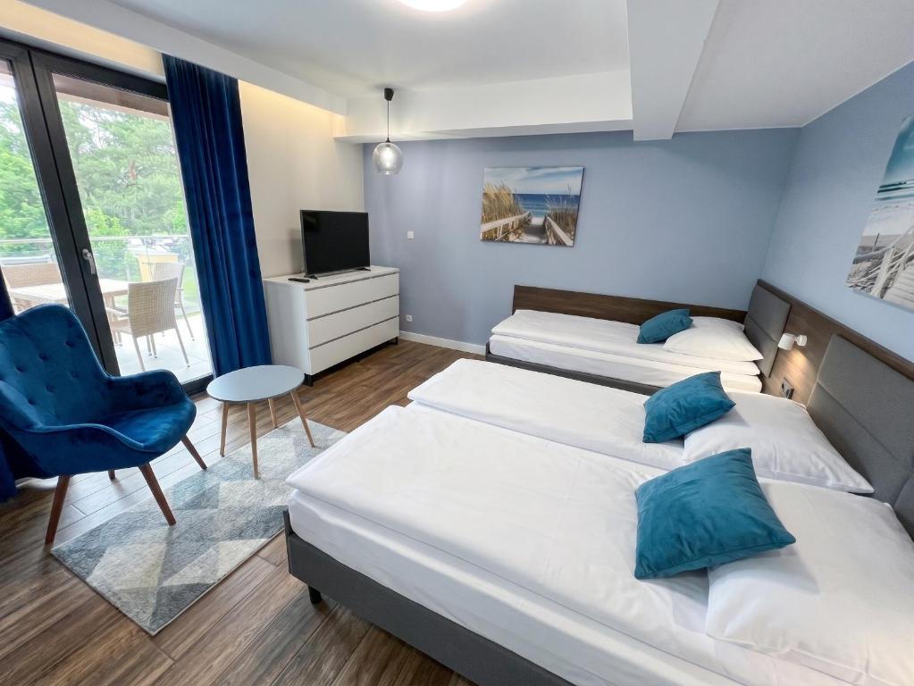 a bedroom with two beds and a blue chair at Villa Continental in Pobierowo