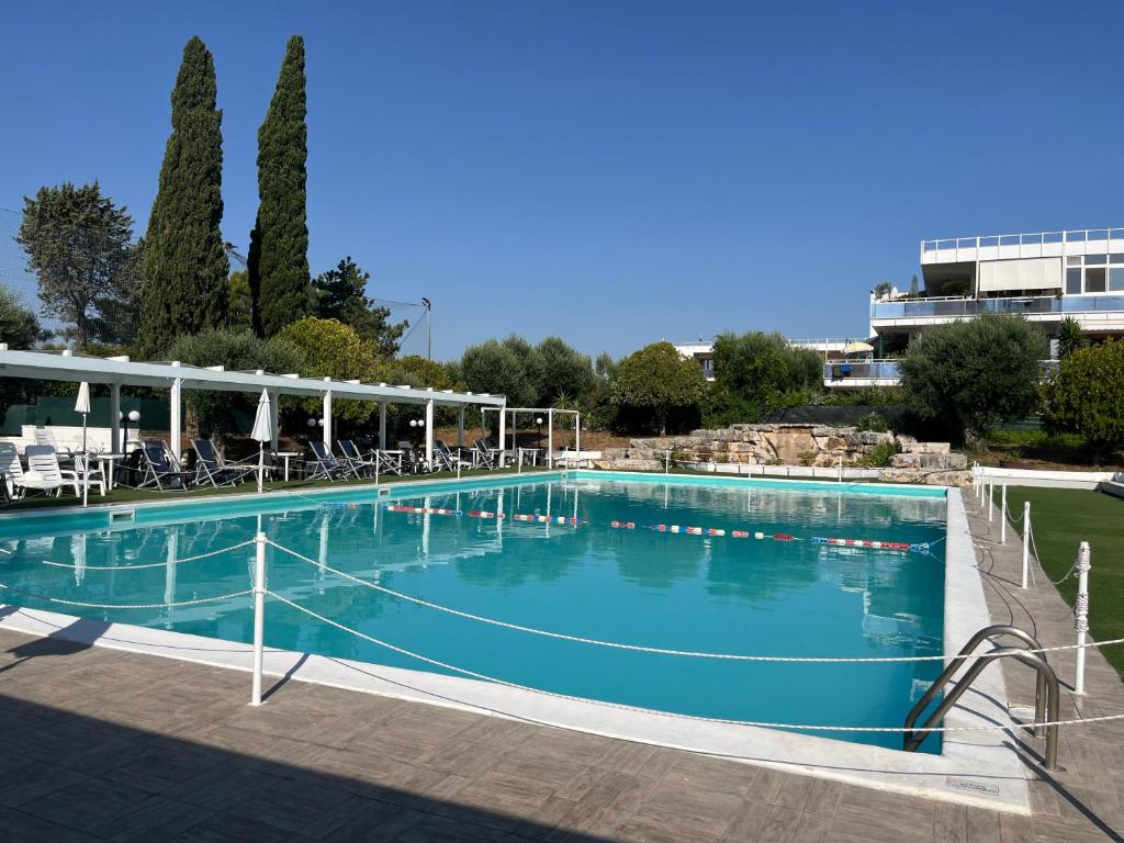 a large blue swimming pool with chairs and trees at Dimora Levante - Pool & Tennis in Noicattaro