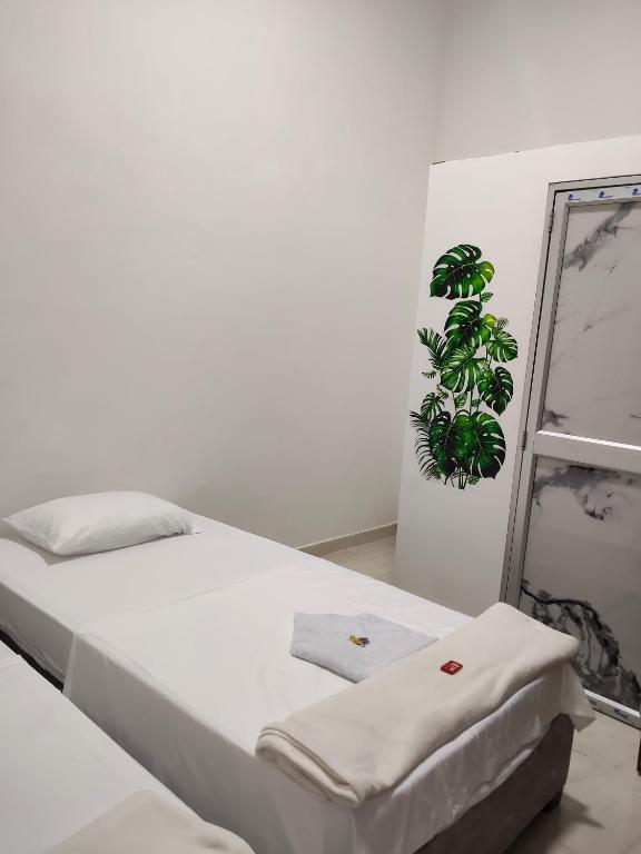 a white bedroom with a bed and a plant at Hospedaje Monasterio in Buga