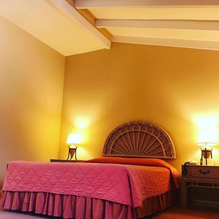 a bedroom with a large bed and two lamps at Aparthotel La Quinta in Santa Cruz de la Sierra