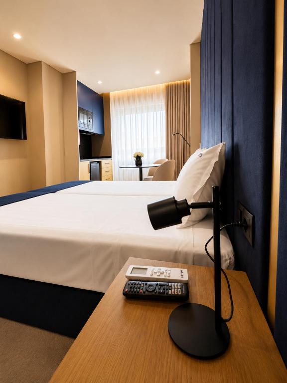 a hotel room with a bed and a desk with a lamp at INOTEL Paços de Ferreira in Paços de Ferreira
