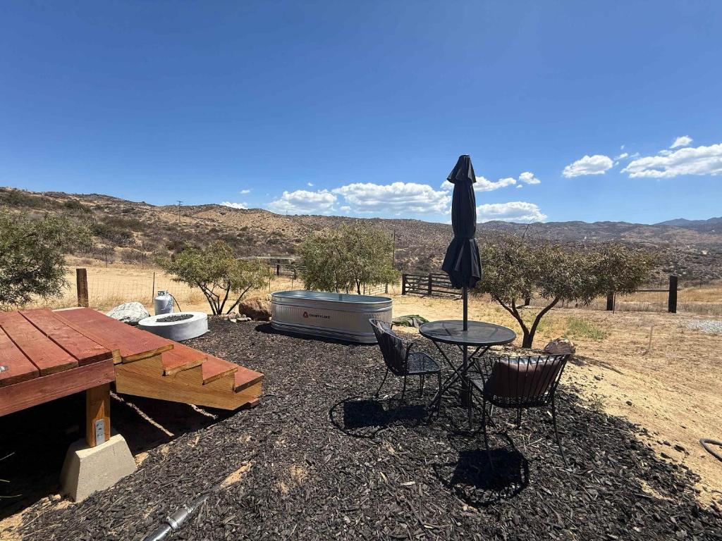 a patio with a table and an umbrella and a tub at Quiet Luxury Tiny Home Retreat Rustic Chic in Aguanga