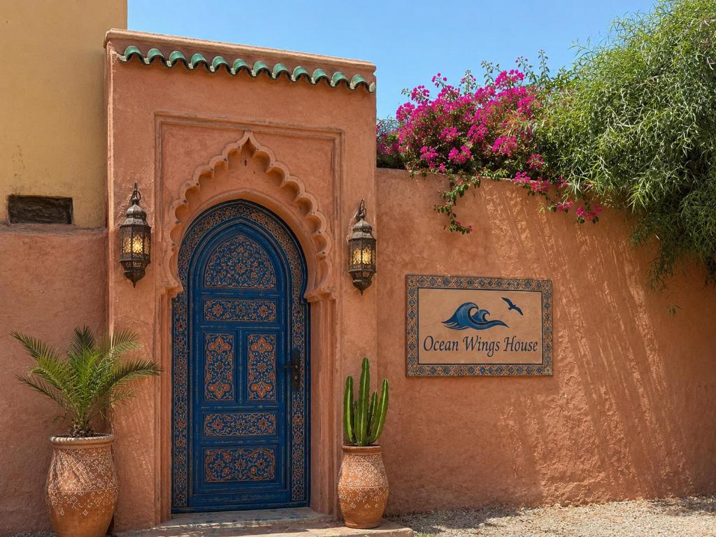 a building with a blue door and a sign on it at Ocean Wings House in Rbat