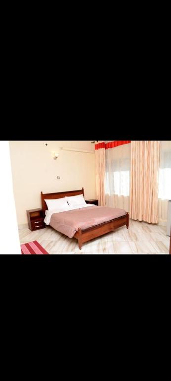 a bedroom with a large bed and a window at Meraki Palate in Entebbe