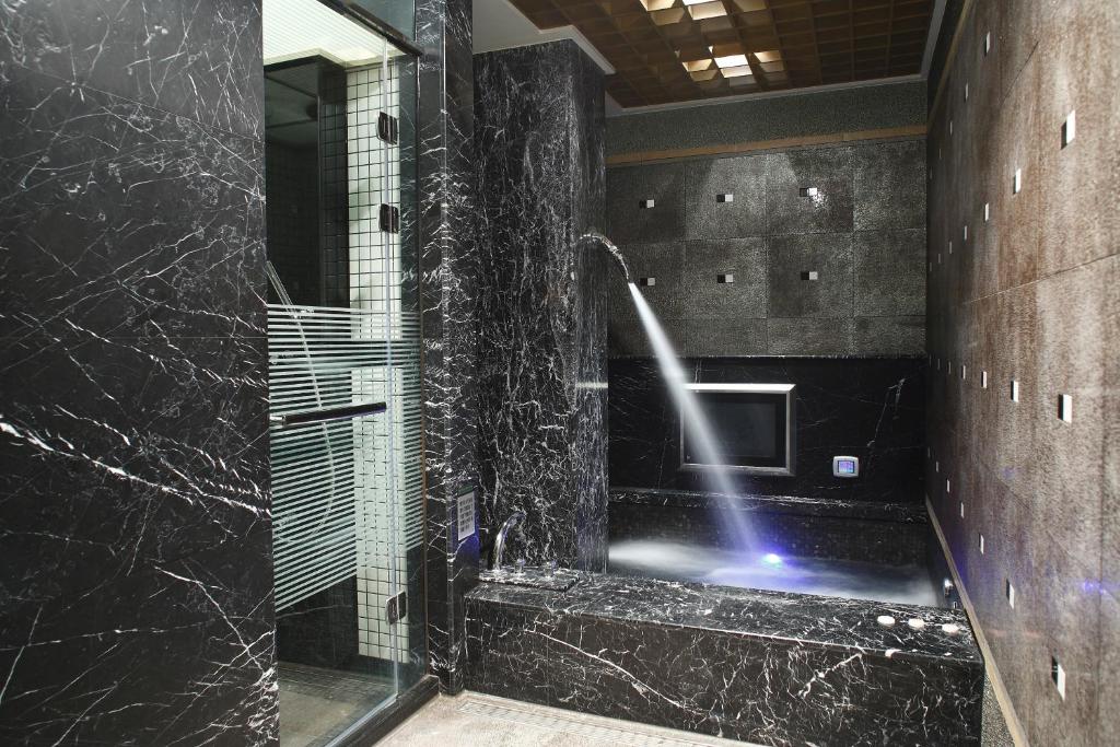 a bathroom with a shower with black marble at Dryad Motel in Tainan