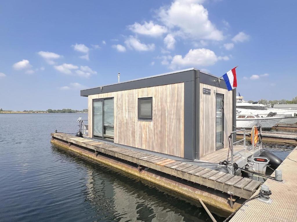 a small building on a dock on a body of water at Jopies Houseboat in Maasbommel