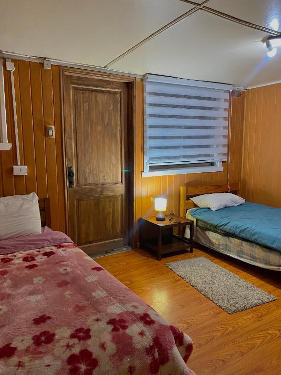 a bedroom with two beds and a window with a table at Cabañas Deisy in Valdivia