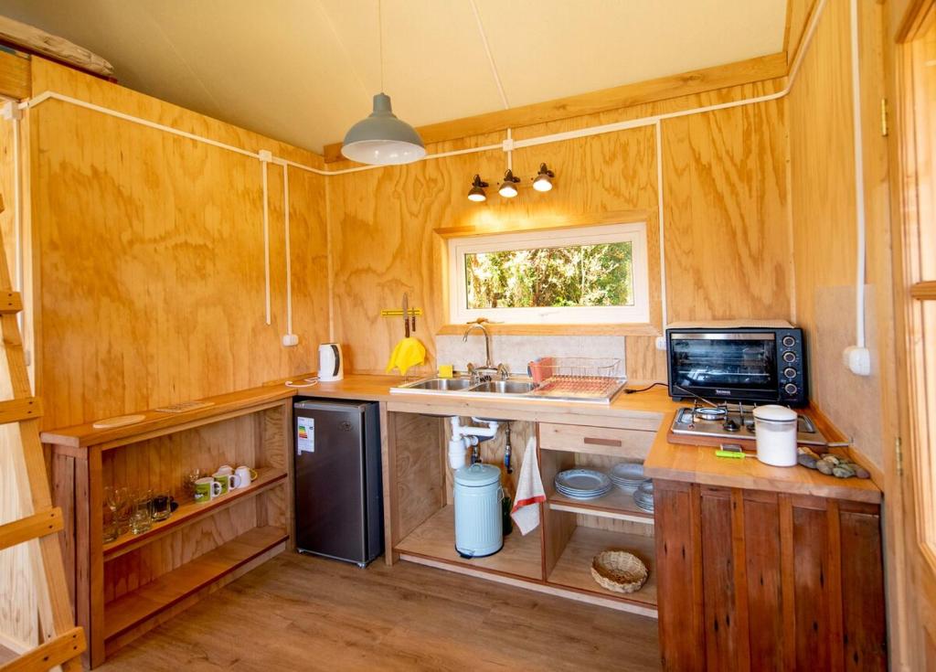 a kitchen with wooden walls and a counter with a computer at Cabaña Raymapu in Puelo