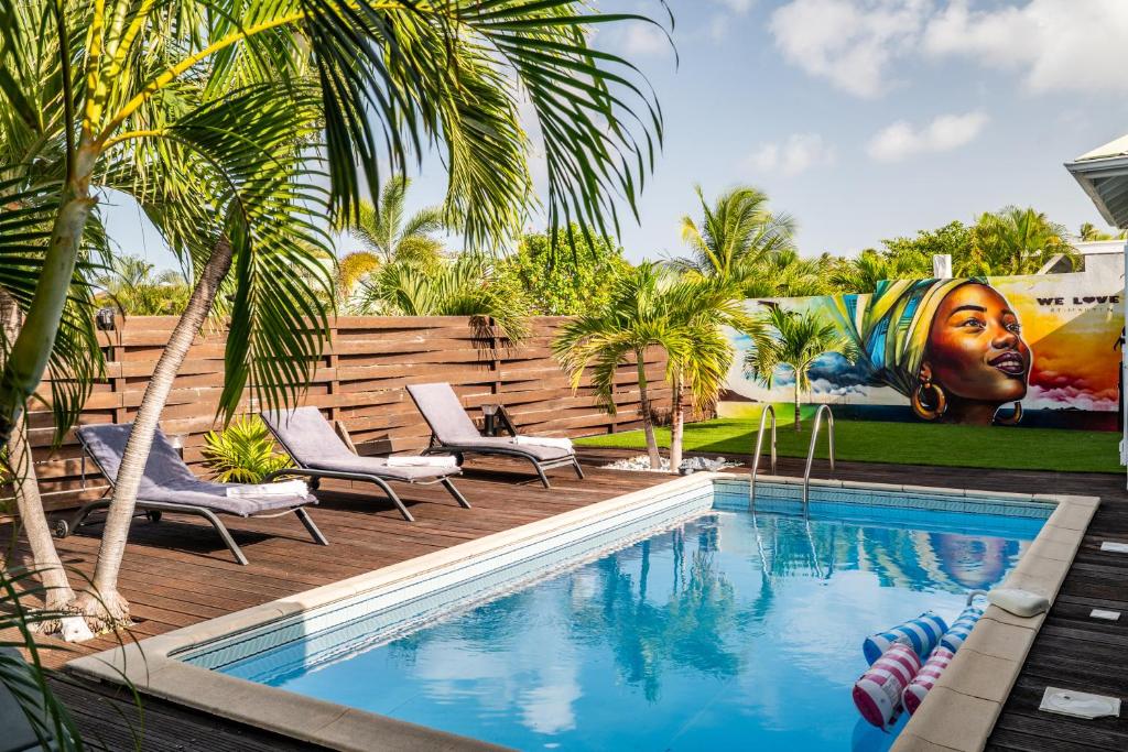 a swimming pool with two chairs and a painting on the wall at Villa Madame in Saint Martin