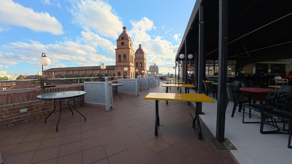 a patio with tables and a building with a clock tower at Hotel Pascana Plaza in Santa Cruz de la Sierra
