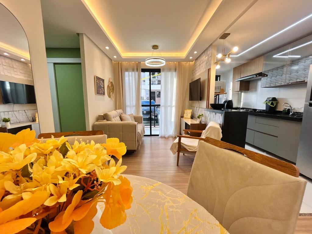 a living room with a table with yellow flowers on it at Lunar Lua Nova 06 in Aracaju