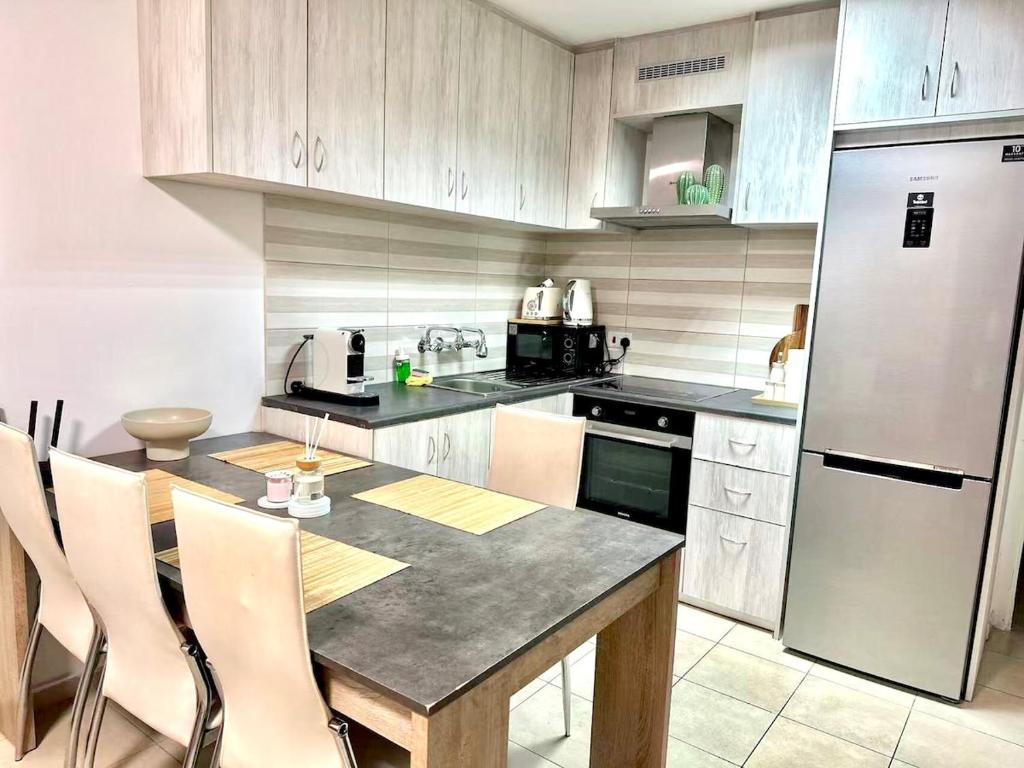 a kitchen with a table and a refrigerator at Arithea Hidden Seaside Heritage 2BR Suite in Paphos