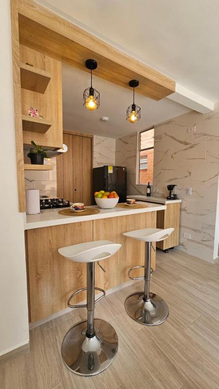 a kitchen with two tables and a counter at Apartamento Urban Paipa in Paipa