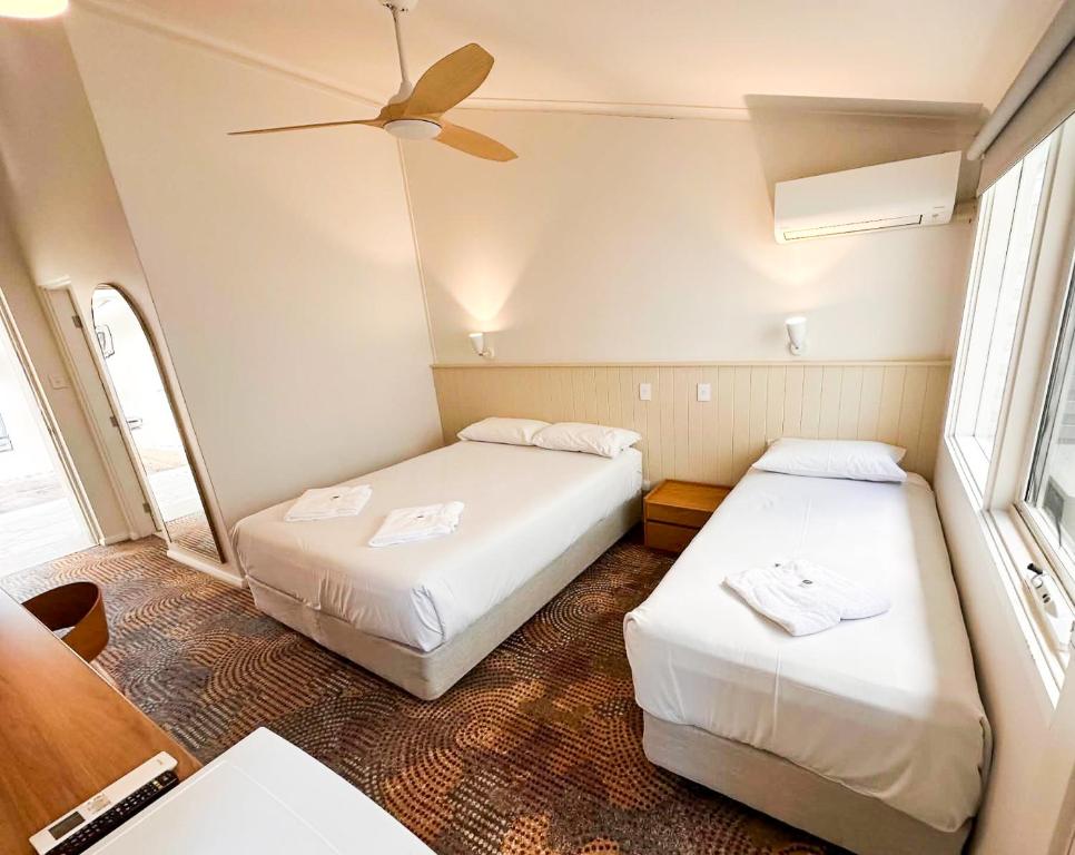 a room with two beds and a ceiling fan at Bateau Bay Hotel in Bateau Bay