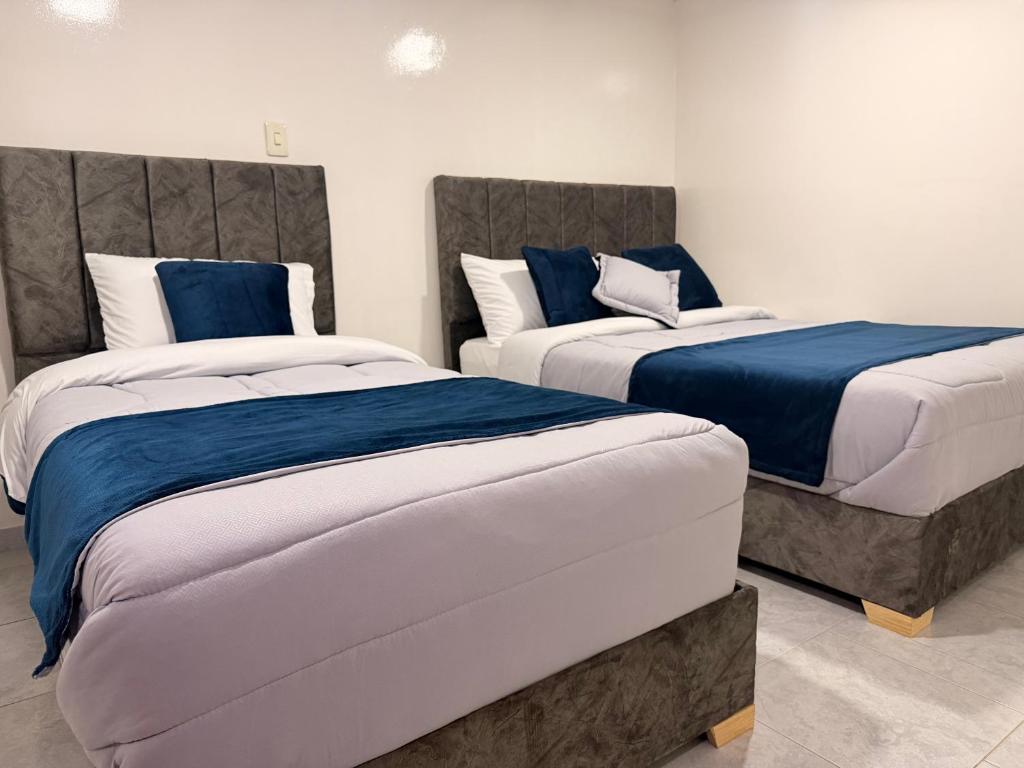 a bedroom with two beds with blue and white sheets at Hotel Hostal Urban18 in Bogotá