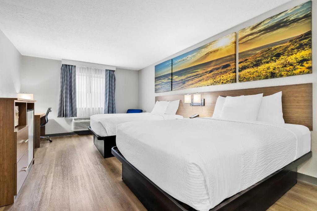 a hotel room with two beds and a desk at Quality Inn Sheridan in Sheridan