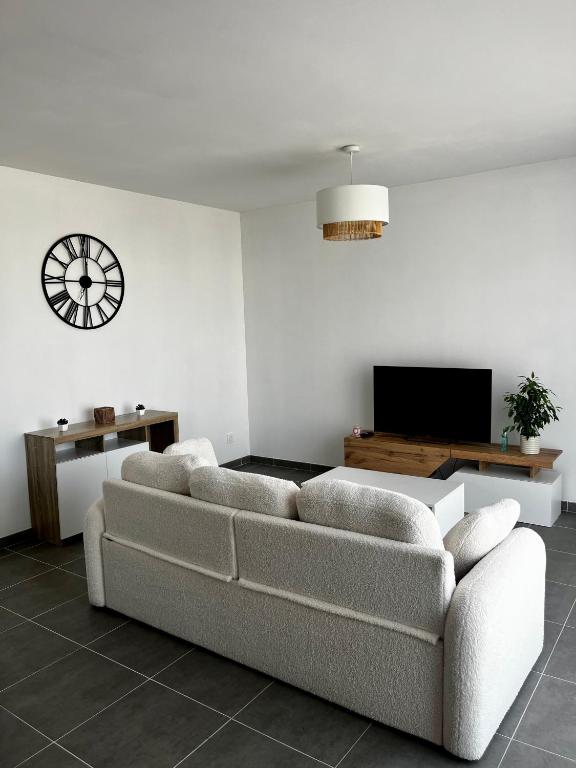 a living room with a couch and a clock on the wall at Maison chaleureuse in Migron
